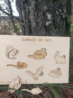 Wooden board with laser-cut animal shapes and text 'animals del bosc' against a natural background.