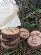 Stack of wooden slices with engraved animal designs and text, placed on grass.